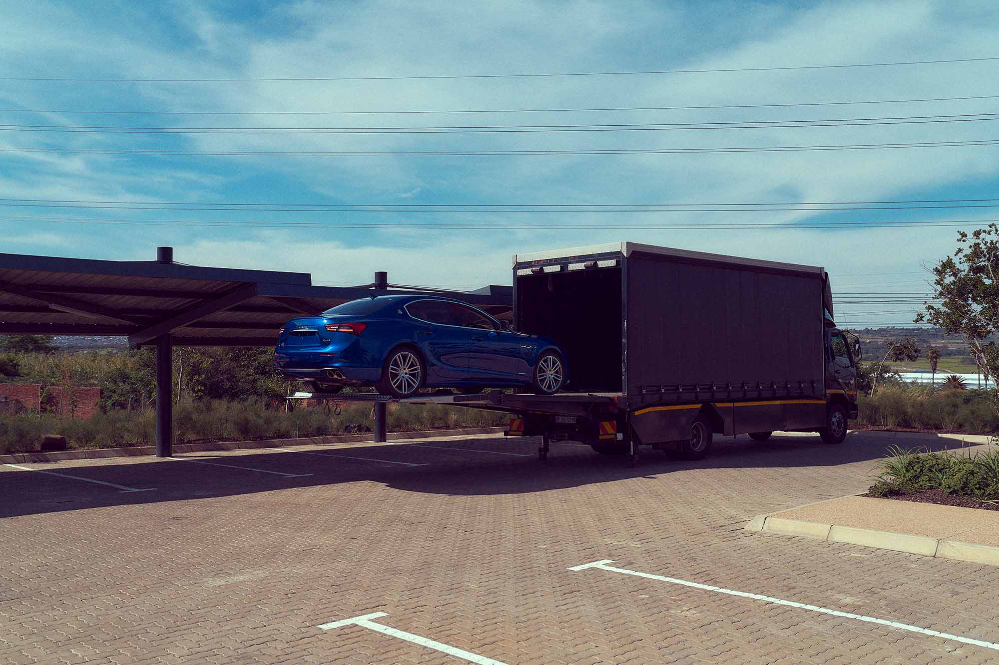Maserati car in a vibrant blue being offloaded in Christchurch. The car's streamlined body, iconic front grille, and stylish headlights exude luxury and performance in this automotive photograph.