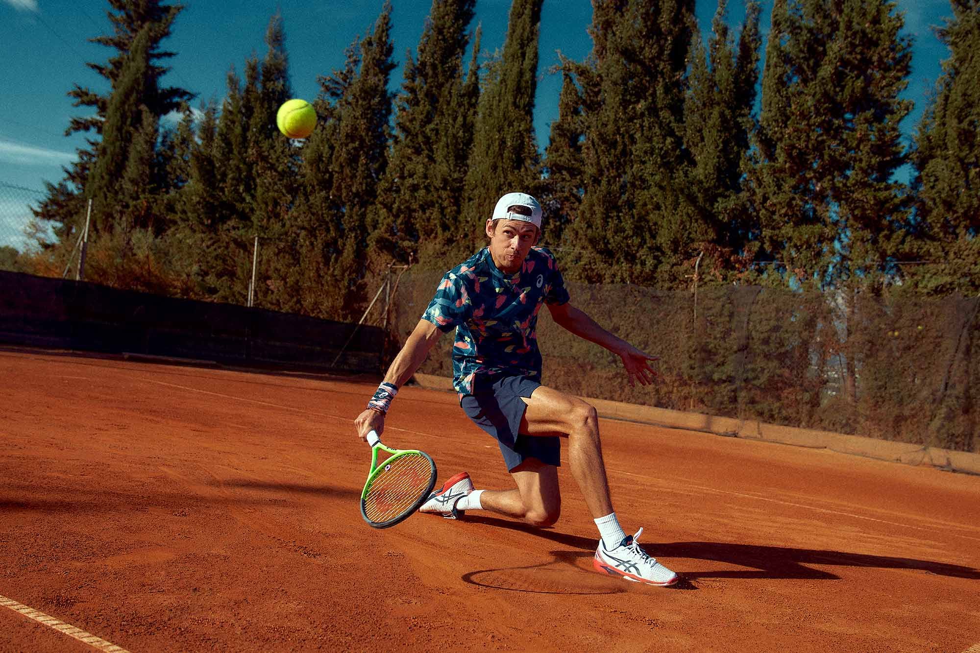 tennis star Alex De Minaur slides while playing a back hand volley on ASICS Europes latest commercial campaign.