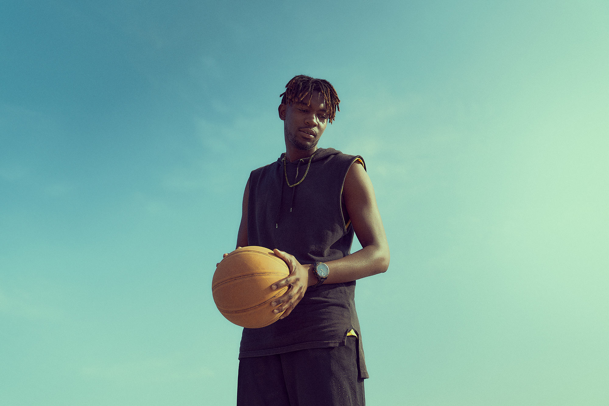 Tissot product watch print campaign featuring basketball players engaged in a one-on-one game at the V&A Waterfront in Cape Town. The photograph is taken using natural lighting, showcasing the players' skill and intensity as they compete. The Tissot watch is prominently displayed, highlighting its presence and association with the exciting sporting event.