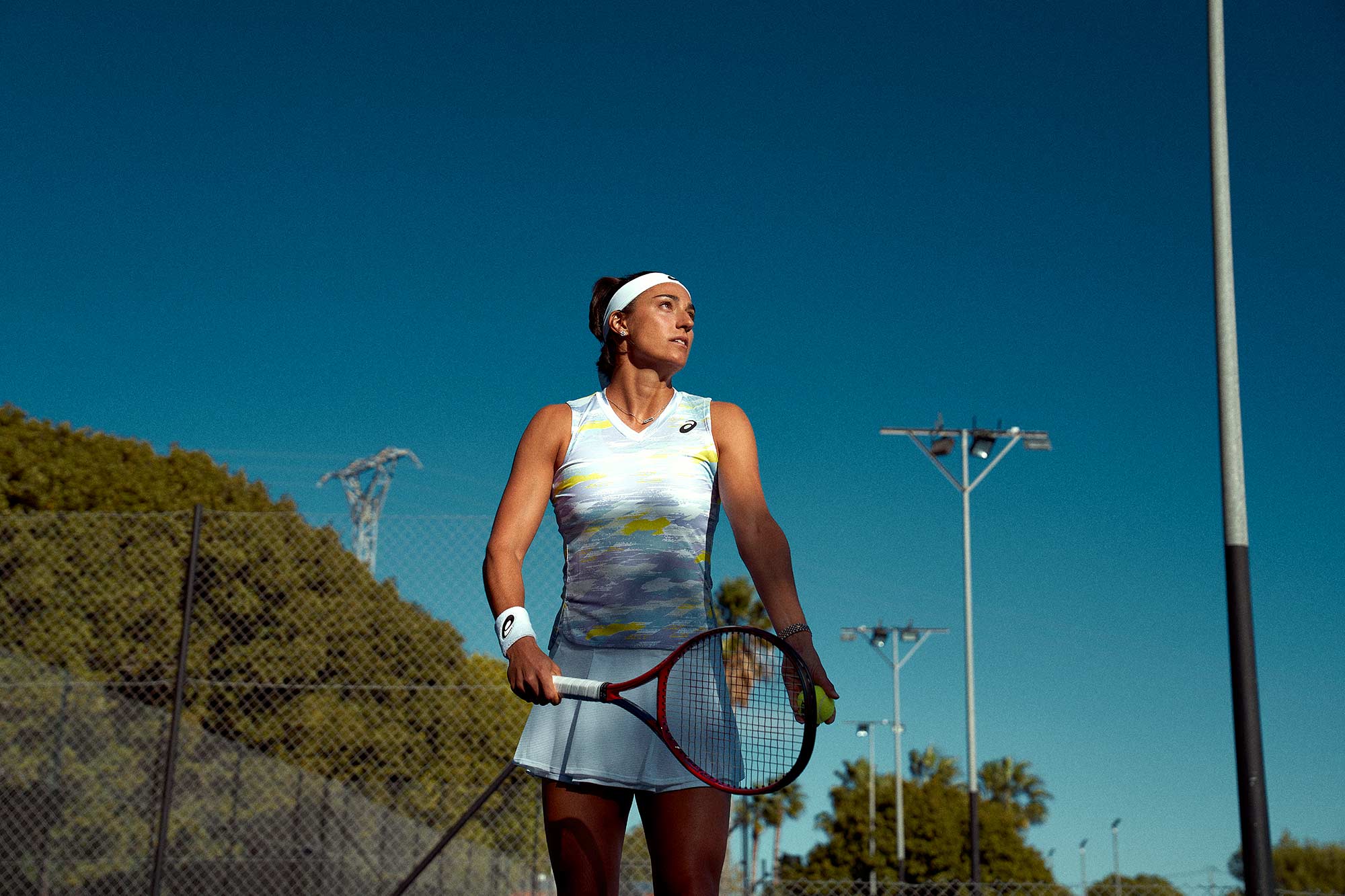 crisp blue sky sets the backdrop as tennis star caroline garcia sets up a serve on hard court